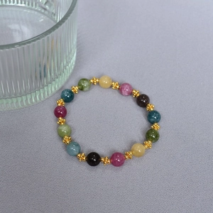 Macro detail of colorful tourmaline beaded bracelet with golden flower petal spacers