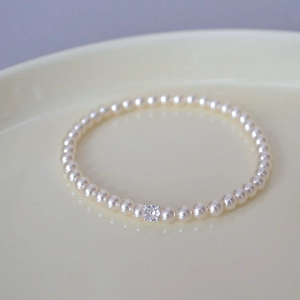 Macro view of high-luster pearl bracelet with a sparkling crystal center on a ceramic tray