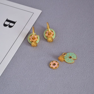Détail de boucles d'oreilles lotus en émail avec pendentifs amovibles en laiton doré