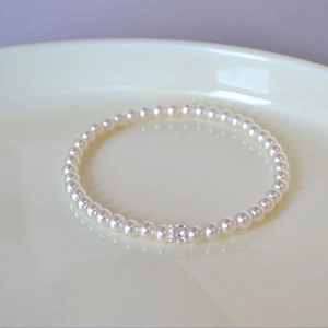 Macro detail of elastic pearl bracelet featuring a sparkling rhinestone centerpiece bead