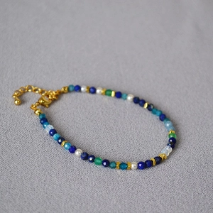 Detail of beaded bracelet featuring lapis lazuli, malachite, pearls and golden clasp