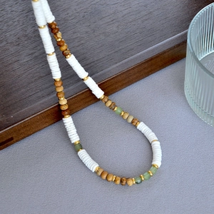 Handmade beaded necklace featuring white shell discs with marble stone and green bead accents