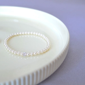 Detailed macro view of white pearl stretch bracelet with a square clear crystal charm