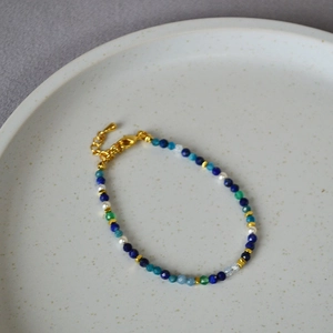 Lapis lazuli beaded bracelet with pearls and gold spacers on a ceramic plate