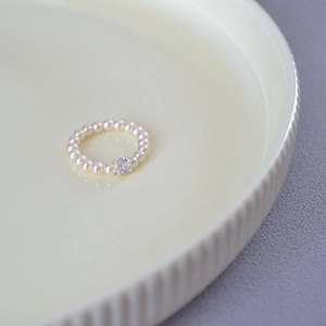Detailed macro view of an elegant pearl ring featuring a central sparkling zircon stone