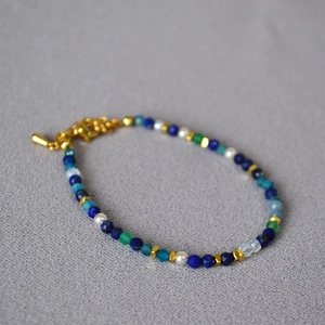 Detailed macro view of handmade beaded bracelet with lapis lazuli and gold lobster clasp