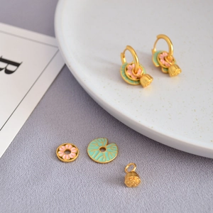 Vue macro détaillée de pendentifs fleurs en émail et feuilles de lotus sur créoles dorées