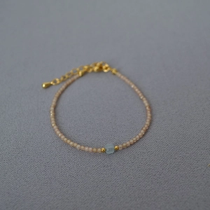 Detailed close-up of beaded bracelet with blue square crystal and gold clasp