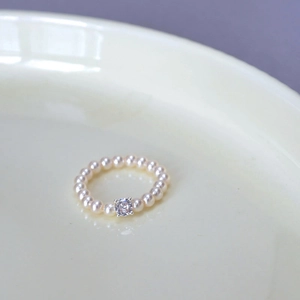Detail of beaded pearl ring featuring a central sparkling zircon in a four-prong setting