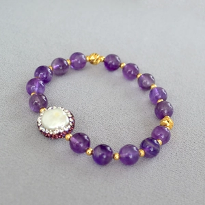 Vue détaillée des perles d'améthyste et de la perle baroque avec accents dorés sur le bracelet