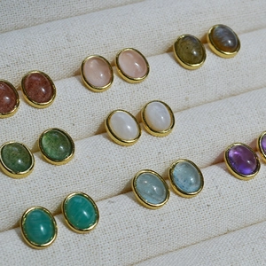 Detail of oval gemstone stud earrings in various colors with gold plated brass settings