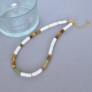 Detail of bohemian beaded necklace with white clay, brown stones, and gold lobster clasp