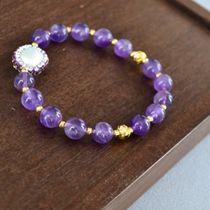 Détail du bracelet en améthyste avec perle d'eau douce sur un plateau en bois
