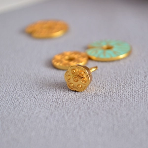 Vue macro de boucles d'oreilles lotus artisanales dorées avec finition émail