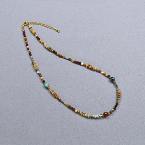 Gros plan du collier de perles colorées avec fermoir mousqueton doré et chaînette