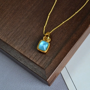 Vue macro détaillée d'un collier en laiton plaqué or avec un pendentif en cristal bleu
