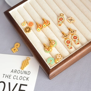 Détails de boucles d'oreilles artisanales en émail et laiton avec motifs floraux