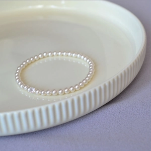 Elegant French style pearl bracelet with a square rhinestone detail in a ceramic dish