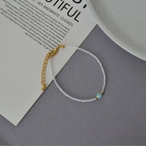 Close-up of beaded bracelet featuring white faceted beads and a blue square gemstone