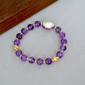 Détail d'un bracelet en améthyste avec pendentif cœur et perle baroque d'eau douce