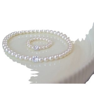 Elegant pearl jewelry set featuring a necklace and ring with sparkling center stones