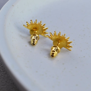 Vintage gold-plated sunburst earrings featuring natural moonstone on a ceramic tray