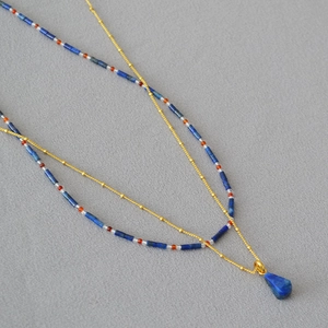 Detailed close-up of double-layer lapis lazuli beaded necklace with a golden droplet charm