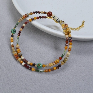 Détail d'un collier bohème avec perles en pierre naturelle et fermoir doré sur une assiette
