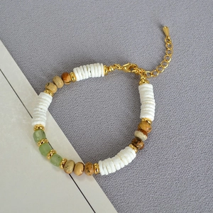 Macro detail of bohemian beaded necklace with white shell discs and green gemstone beads