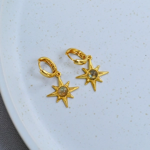 Golden North Star hoop earrings with labradorite stone on a white ceramic plate