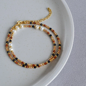 Detail of baroque pearl and gemstone beaded necklace with golden clasp on ceramic plate