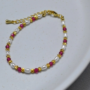 Macro shot of pearl and red corundum beaded necklace with golden textured accents