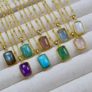 Close-up of geometric natural stone pendants in gold plated brass settings on chain