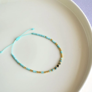 Macro detail of sky blue cylinder beads and adjustable sliding knot on bohemian bracelet