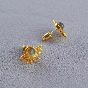 Detailed shot of sunburst brass earrings with moonstone inlay and gold finish