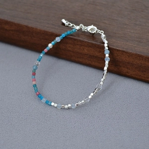 Detail of handcrafted French beaded necklace with blue and pink stones and silver charms