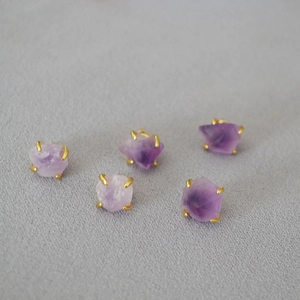 Macro view of purple amethyst raw stones in four-claw gold-plated settings