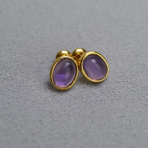 Detailed macro view of gold plated brass stud earrings with oval purple amethyst stone