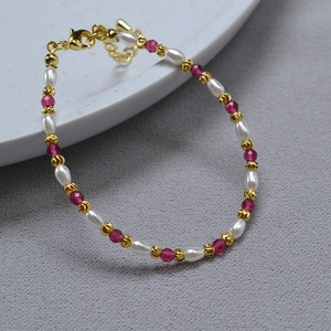 Close-up of elegant rice pearl necklace with red ruby beads and golden lobster clasp