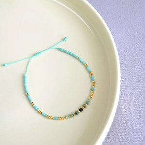 Detail of bohemian turquoise beaded bracelet with gold accents and adjustable blue cord
