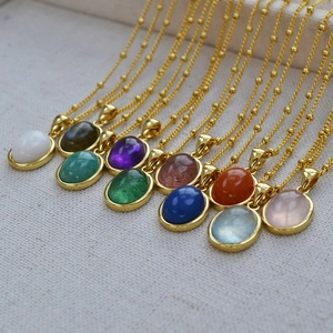 Close-up of ten oval natural stone pendants in diverse colors with gold beaded chains