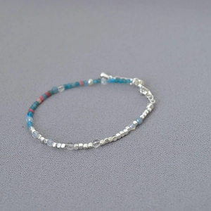 Macro detail of French beaded necklace with silver metal cubes and pastel stones