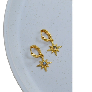 Chic gold starburst hoop earrings with labradorite stone center on ceramic background