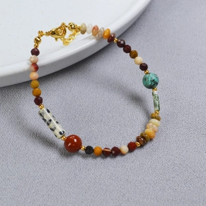 Détail du bracelet en pierres fines colorées avec fermoir doré sur fond gris