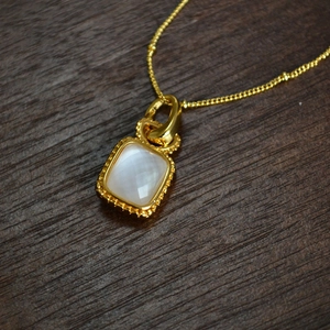 Vue macro d'un pendentif en pierre de lune facettée sur un collier en laiton doré