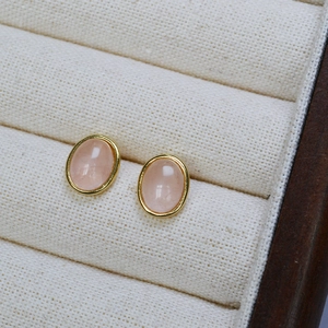 Macro view of oval rose quartz gemstones with gold bezel setting in a display box