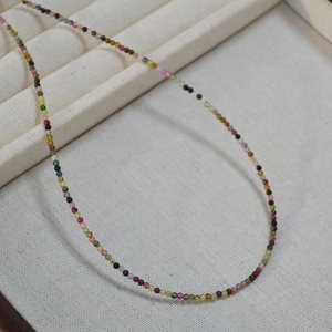 Detail view of 2mm colorful tourmaline beads necklace on a neutral jewelry tray