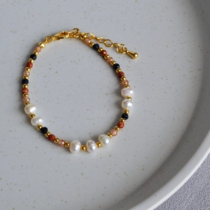 Detail of baroque pearl and gemstone beaded bracelet with gold clasp and extender chain