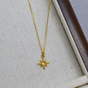Macro detail of gold plated star pendant with labradorite on a beige linen jewelry tray