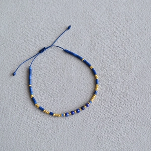 Macro view of blue and gold beaded bracelet with faceted gemstones and pull cord
